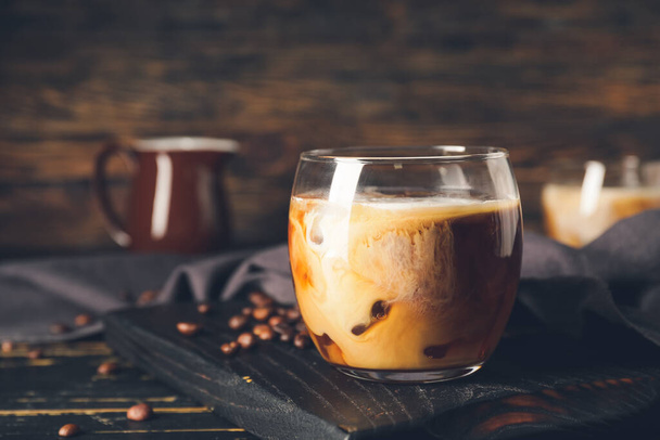 Glass of delicious cold brew coffee with milk on dark wooden table - Photo, Image