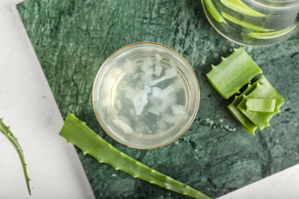 Board with glass of aloe juice and leaves on white background - Фото, изображение