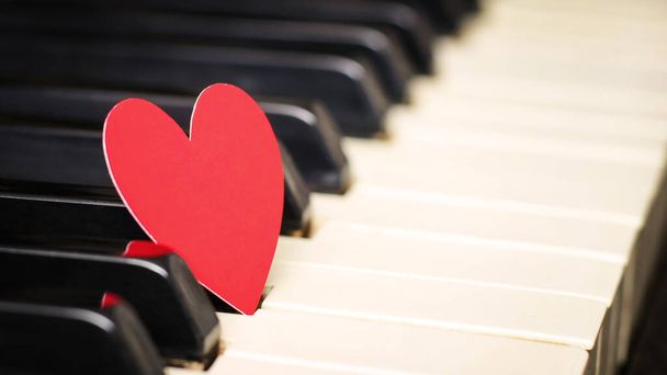 Small red paper heart on piano keys. Concept of love, valentine's day. Toned in warm color - Foto, immagini