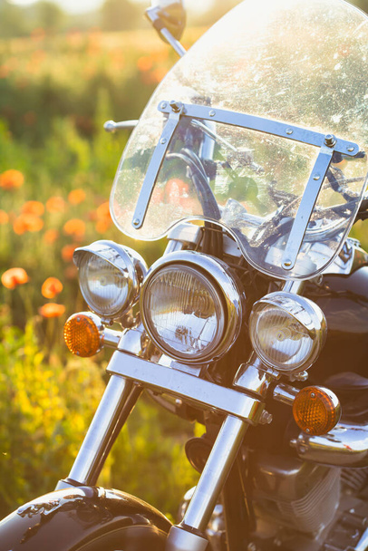 Motorcycle closeup in magic sunset in the poppy field. Travel and sport, speed and freedom concept - 写真・画像