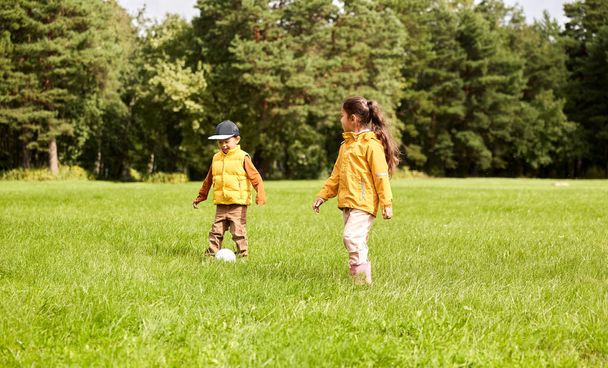 子供時代,レジャーゲームや人々の概念 – 夏の公園でボールのサッカーをして幸せな男の子と女の子 - 写真・画像