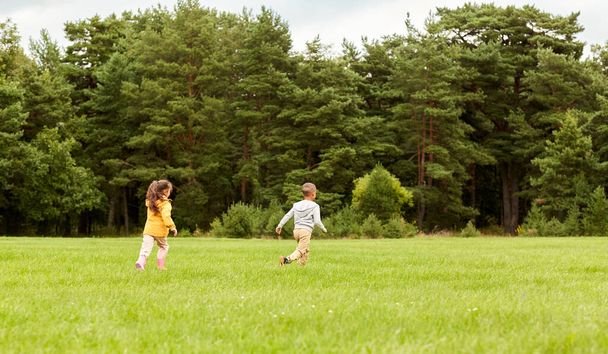 childhood, leisure and people concept - children playing tag game and running at park - Foto, imagen