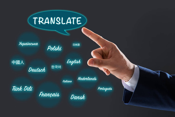 Translator pointing at virtual screen with names of different languages on grey background, closeup - Photo, image