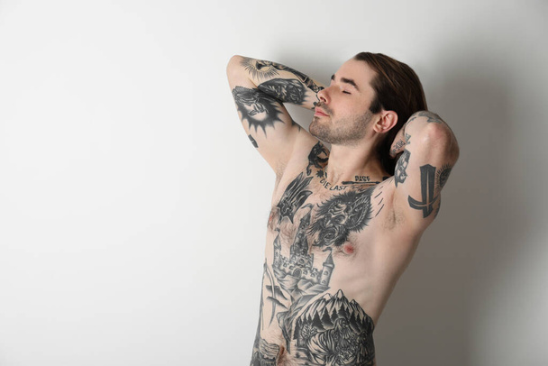 Young man with tattoos on body against white background - Photo, Image