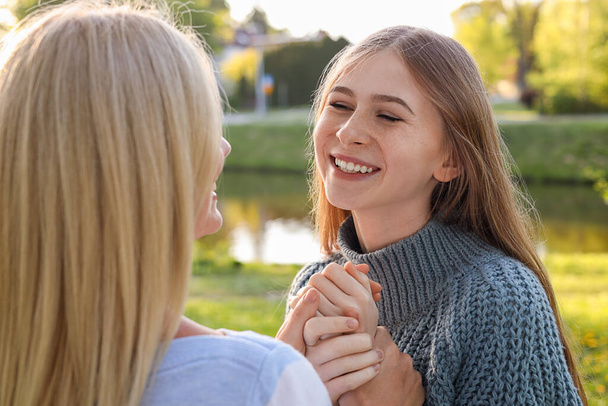 Happy daughter with her mother spending time together in park on sunny day - Photo, image