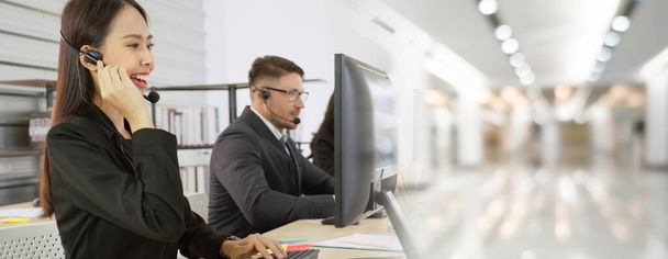 Business people wearing headset working in office to support remote customer or colleague. Call center, telemarketing, customer support agent provide service in broaden view . - Photo, Image