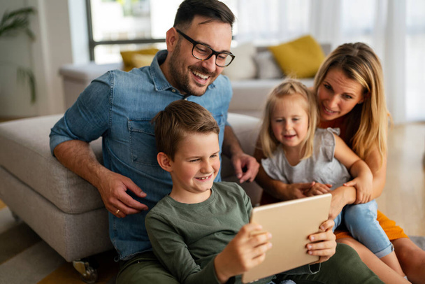 Happy young family having fun time at home. Parents with children using digital device. Education parenting happinness concept. - Fotó, kép