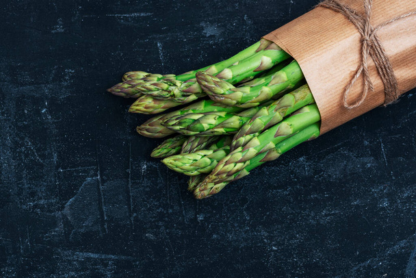 Fresh green asparagus on black table. Healthy vegan food concept. Top view, flat lay. - Fotó, kép