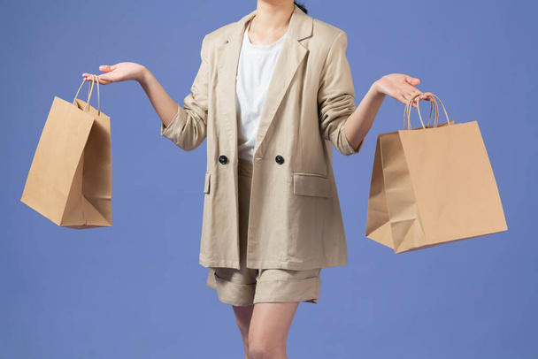 όμορφη ευτυχισμένη γυναίκα κρατώντας τσάντες ψώνια, απομονωμένη σε μωβ - Φωτογραφία, εικόνα
