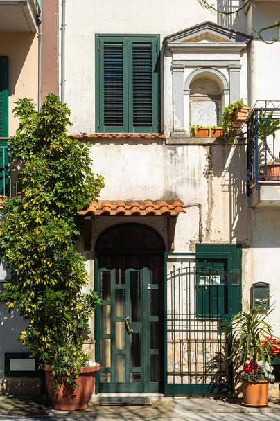Small historic courtyards on old streets in southern Italy. Flowers in pots and antique wooden doors in stone medieval houses. Walk through the old European city, tourism. - Zdjęcie, obraz
