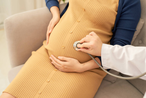 Kadın doktor, koltukta hamile kadını muayene ediyor.. - Fotoğraf, Görsel