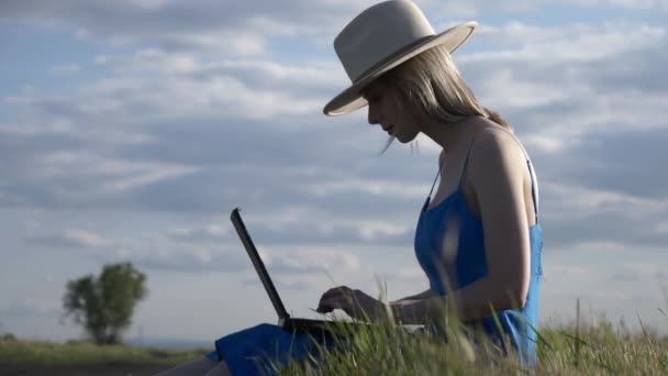Kobieta z laptopem siedzi na wiejskiej drodze - Materiał filmowy, wideo