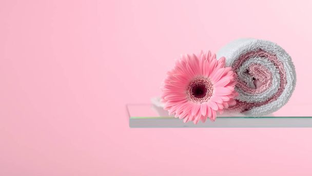 Spa composition with pink gerber and towels on a pink background. Copy space. - Photo, Image