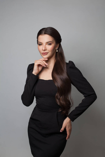 Glamorous brunette model in elegant black dress standing on white background - Фото, изображение