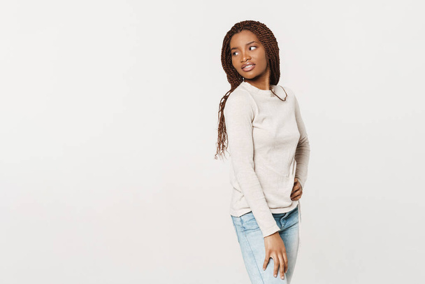 Jeune femme noire avec des nattes souriantes et regardant de côté isolé sur fond blanc - Photo, image