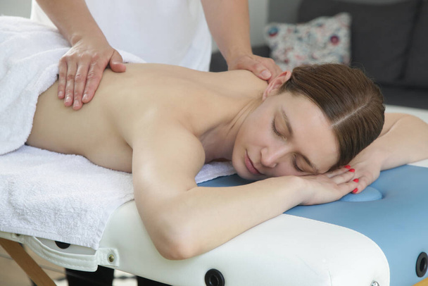Mobilní masážní služba. Mladá žena s měkkým střílením relaxovat masáž doma. - Fotografie, Obrázek