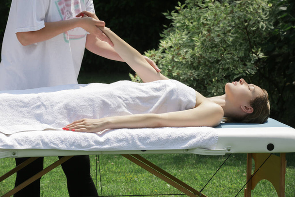 Lázeňská masáž venku. Mobilní masážní služba. Mladá žena těší měkké střílení relaxační masážní zážitek na otevřeném vzduchu ošetření. - Fotografie, Obrázek