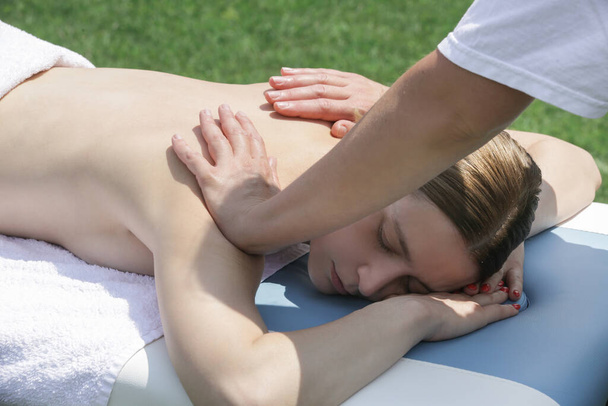 Спа массаж на открытом воздухе. Мобильный массаж. Молодая женщина наслаждается мягкой съемки расслабляющий массаж опыт на открытом воздухе лечение. - Фото, изображение