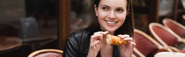 vidám nő kezében frissen sült croissant kültéri kávézó Párizsban, banner - Fotó, kép