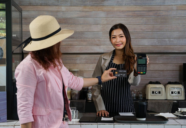 Клієнт платить за каву кредитною карткою і офіціантом, щоб сканувати з мобільним EDC за лічильником, вибірковий фокус                                                            - Фото, зображення