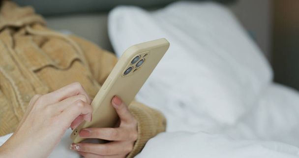 Nainen koskettaa matkapuhelinta sängyssä - Valokuva, kuva