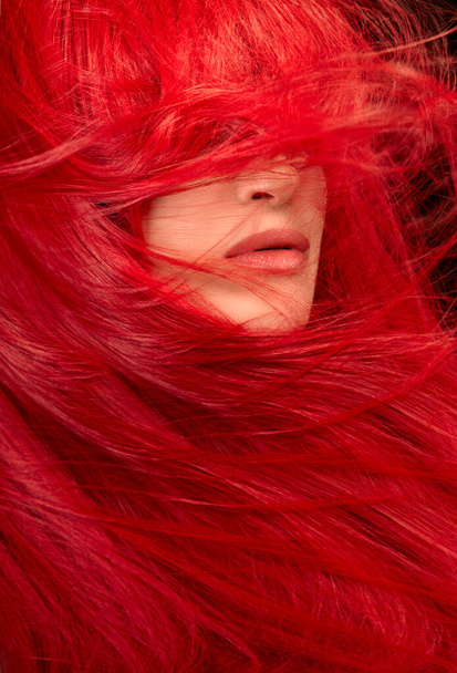 Szépség portré egy nő szélfútta egészséges festett hosszú vörös haj, amely a szemét egy hajápolási és divat koncepció. Függőleges formátum - Fotó, kép