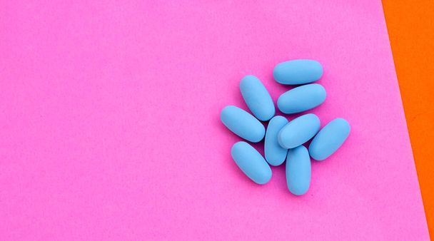 PrEP (Pre-Exposure Profylaxe) blauwe pillen gebruikt om HIV Blue pillen in plastic flessendoppen op roze papieren oppervlak te voorkomen - Foto, afbeelding