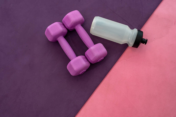 brand new dumbbells kettlebell ball with sand water gums randomly arranged on pink and cherry mats. The concept of sports. Sports hall concept - Photo, Image