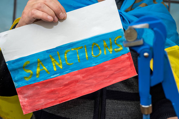 плакат в руках мужчин с санкционированием для России. цілковита ізоляція для терористичної держави. - Фото, зображення
