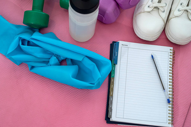 sneakers kettlebell water notebook op sportmat liggen. Concept sportuitrusting - Foto, afbeelding