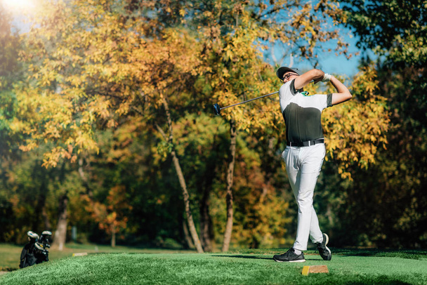 Fiatal golfozó a tee box, üti a labdát a vezető klub egy napsütéses őszi napon - Fotó, kép
