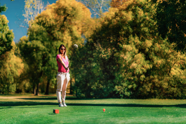 Piękna golfistka przygotowuje się na tee box - Zdjęcie, obraz