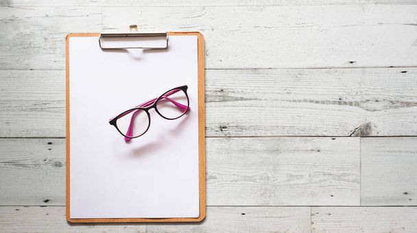 Glasses on blank document on wood clipboard on white wooden table background top view copy space,Business concept - 写真・画像