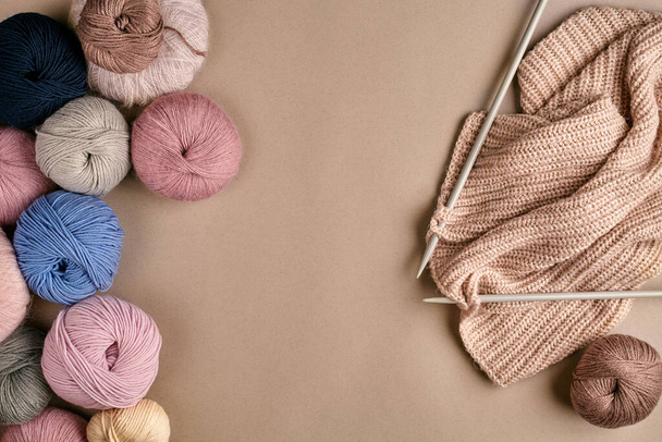 Set of colorful wool yarn and knitting on knitting needles on beige background. Knitting as a kind of needlework. Colorful balls of yarn and knitting needles. Top view. Still life. Copy space. Flat - Photo, Image