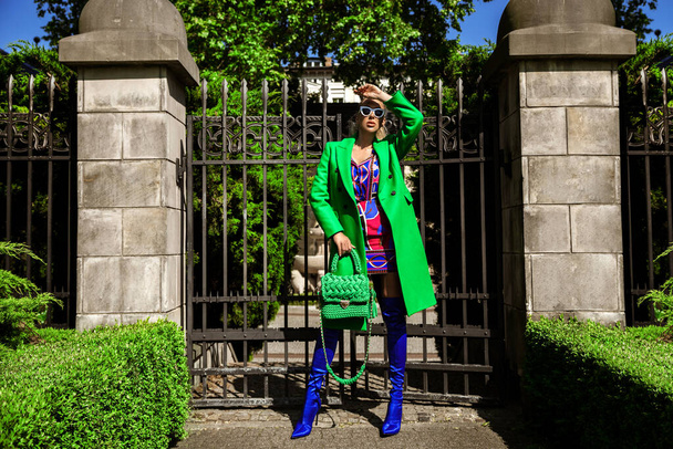 Spring, summer fashion. High fashion model. Glamour, stylish elegant woman. Female model in colorful dress and Trendy green  coat in the city. Outdoor shoot. Casual, urban style. Vogue. - Photo, Image