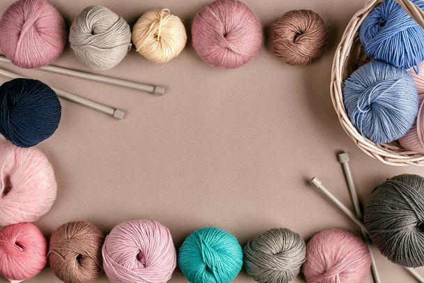 Set of colorful wool yarn on beige background. Knitting as a kind of needlework. Colorful balls of yarn and knitting needles. Top view. Still life. Copy space. Flat lay. Frame of tangles of knitting - Photo, Image