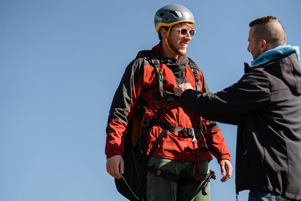 A man helping paragliding pilot to prepare for flight. - Photo, image