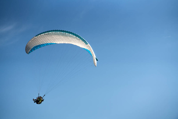 A paraglider in the blue sky. The sportsman flying on a paraglider. - Foto, Imagem