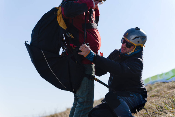 A man helping paragliding pilot to prepare for flight. - Photo, image