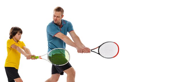 Ready position. Professional tennis player, instructor shows basic techniques in game of tennis to school age boy. Concept of sport, achievements, hobby, skills and ad. Child learning to play tennis. - 写真・画像