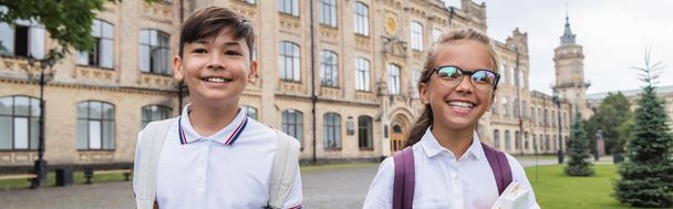Happy interracial schoolkids with backpacks standing outdoors, banner  - Фото, зображення