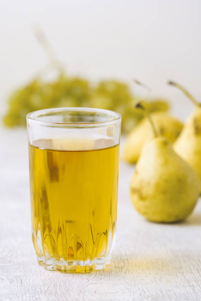 Juice of pears and grapes in a glass on a white wooden background - Photo, Image