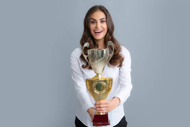 Young beautiful woman holding trophy over grey background. Woman holding a trophy - Foto, Bild