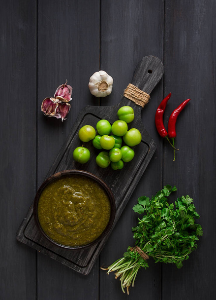 Tkemali sauce, traditional Georgian cuisine, green cherry plum, with ingredients for sauce, cilantro, mint, hot pepper, garlic, on a wooden table, close-up, rustic, food background, no people, selective focus, sauce, green sauce, tkemali, georgian cu - Foto, imagen