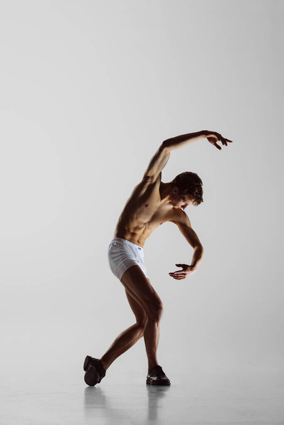 Solo. Express feelings by movements. Contemp dance, performance. Young flexible shirtless man in underwear dancing isolated on gray background. Art, music, beauty. Healthy lifestyle concept - Fotografie, Obrázek
