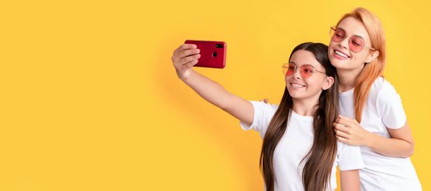Mother and daughter child banner, copy space, isolated background. mom and kid bloggers. lovely woman and girl take selfie with smartphone. selfie family - Foto, immagini