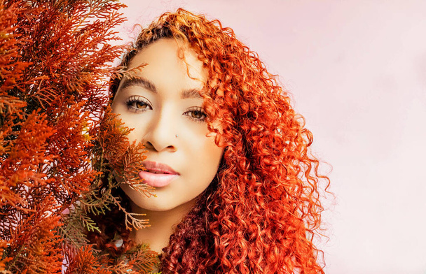 taiteellinen kauneus muotokuva kihara punertava hiukset tyttö vaaleanpunainen tausta punaisia kukkia syksyllä eristetty - Valokuva, kuva