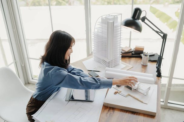 Selective focus, Asian female architect or engineer Currently considering materials for designing modern condominiums. Asian female architect or engineer Sit and analyze, design projects in the office - Photo, Image