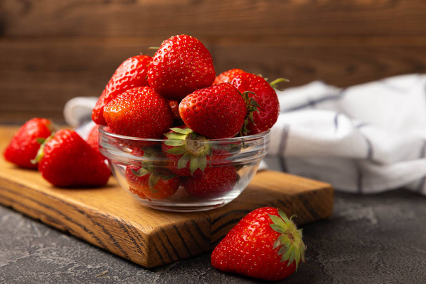 Fresh ripe strawberries in a plate on a black texture background.Vegetarian organic berry.Healthy food.Vitamins.Copy space.Place for text - 写真・画像