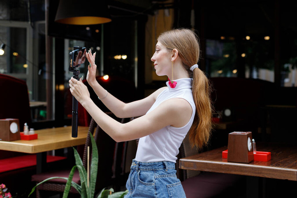 mujer con smartphone toma fotos de sí misma en la ciudad en verano - Foto, Imagen